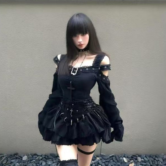 Woman wearing gothic-style black mini dress with off-shoulder detail, standing against a concrete wall