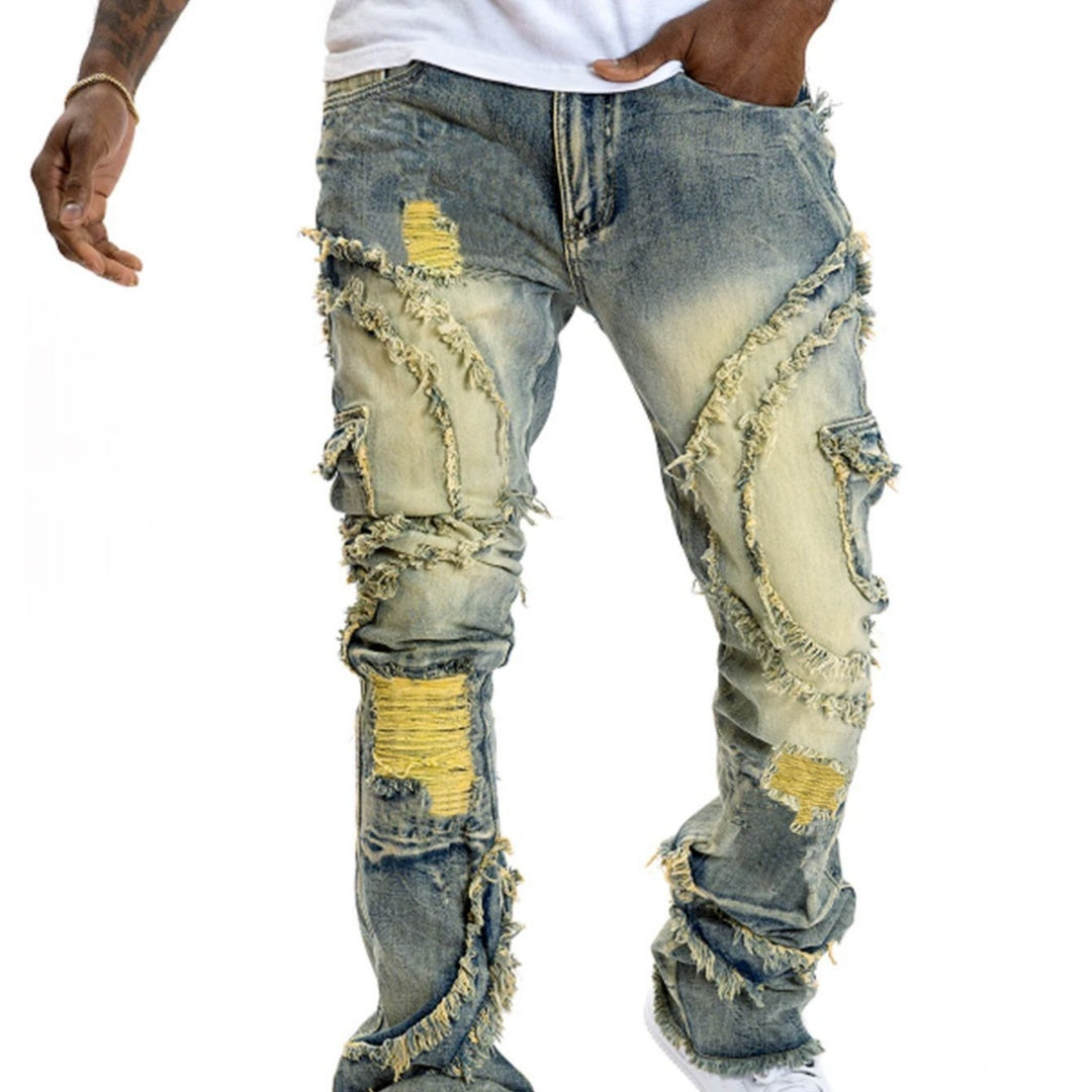 Man wearing yellow patchwork fringe jeans with distressed detailing and flared legs, front view.