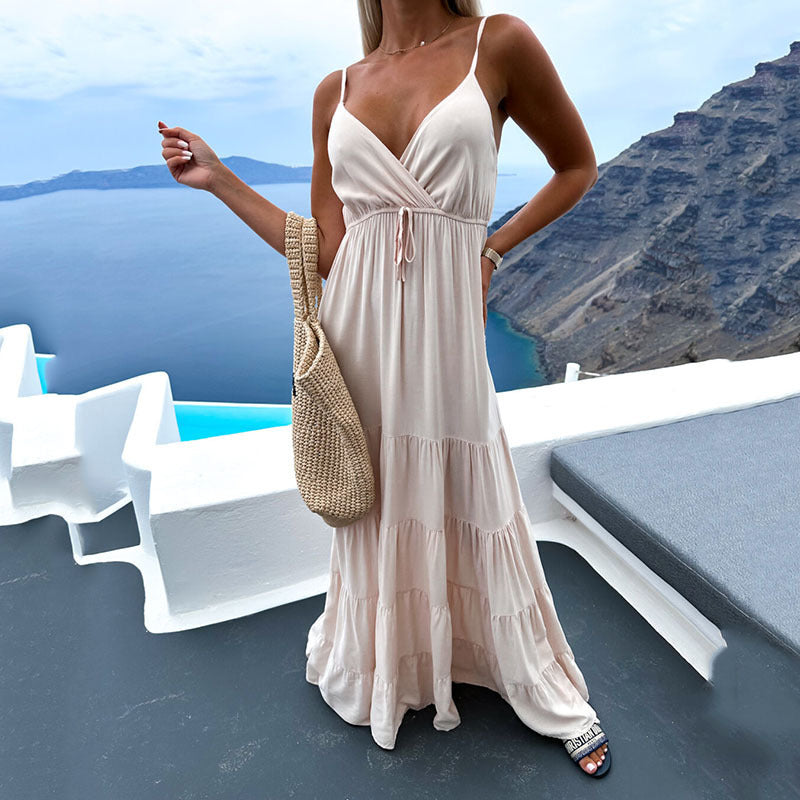 Woman wearing flowing white V-neck maxi dress with tiered skirt on sunny balcony with sea view