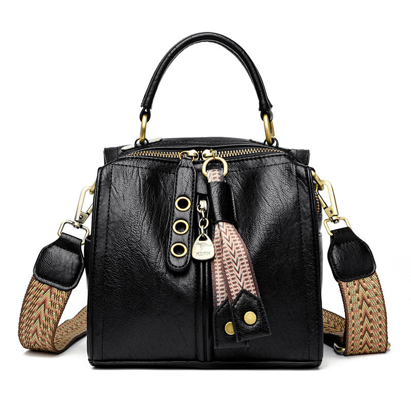 Black messenger bag with wide adjustable strap and tassel detail