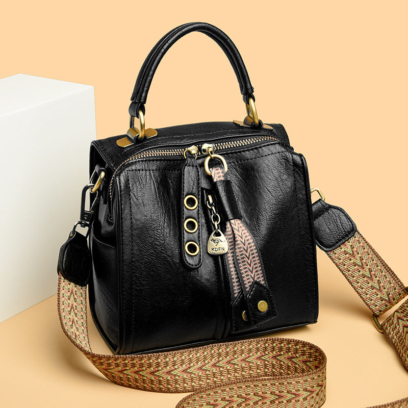 Black messenger bag with wide strap and tassel detail