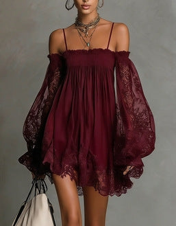 Woman wearing a wine red flowing mini dress with lace sleeves, smocked neckline, and adjustable shoulder straps.