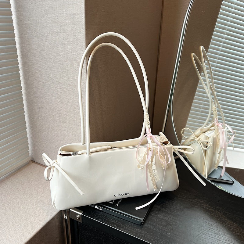 White pillow handbag with knotted ribbon detail on top of the book
