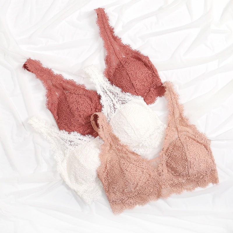 Lace bralette and underwear sets in rose, ivory and peach tones, flat lay on white fabric
