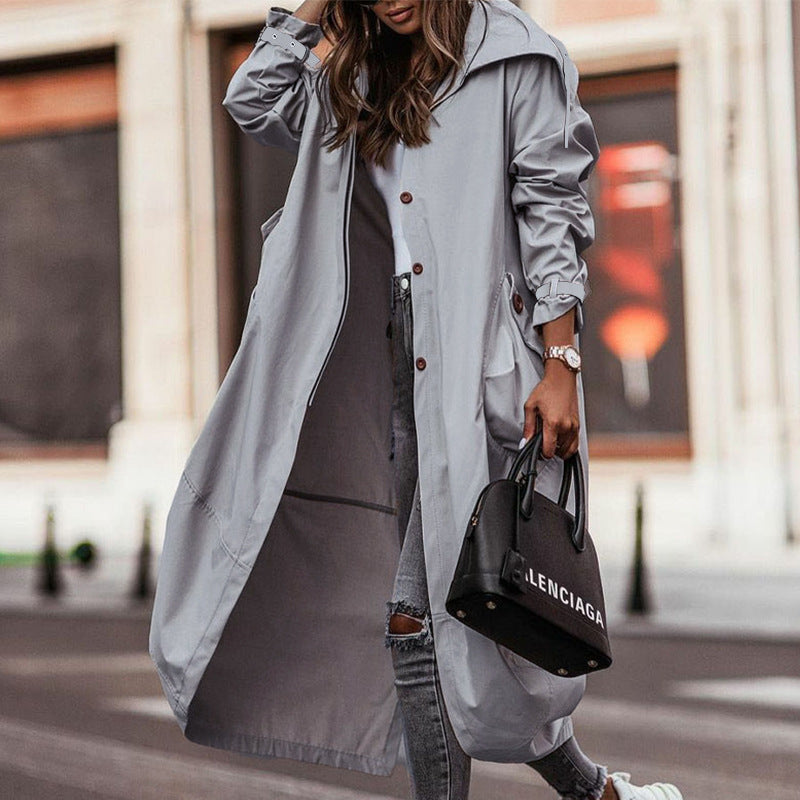 Woman wearing light gray long lapel trench coat, walking on street