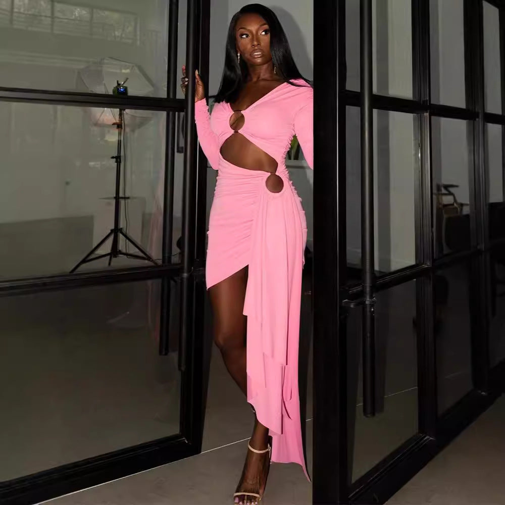 Woman wearing a bright pink off-shoulder asymmetrical dress with ruched details and front ring accent, posing indoors.