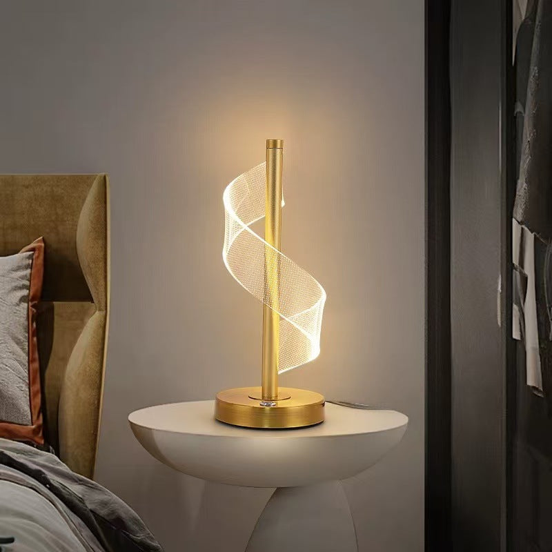 Spiral LED table lamp glowing warmly on a bedside table