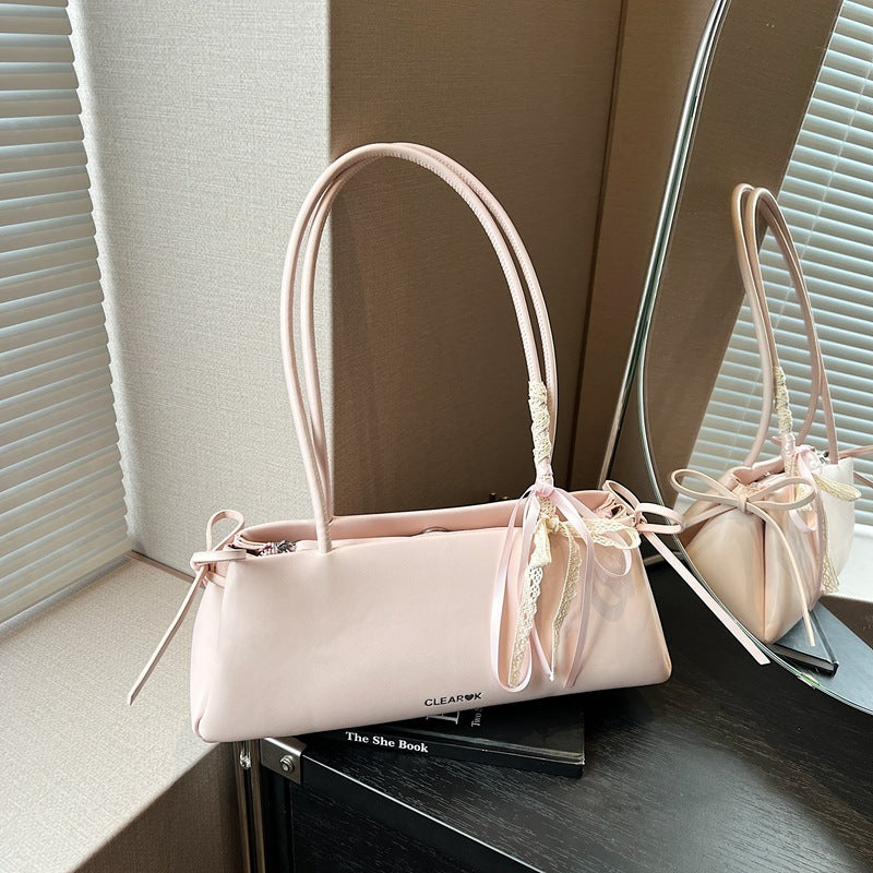 Pink pillow handbag with knotted ribbon detail on top of the book