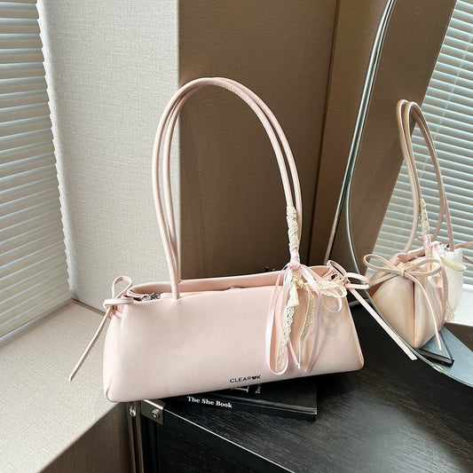 Pink pillow handbag with knotted ribbon detail on top of the book