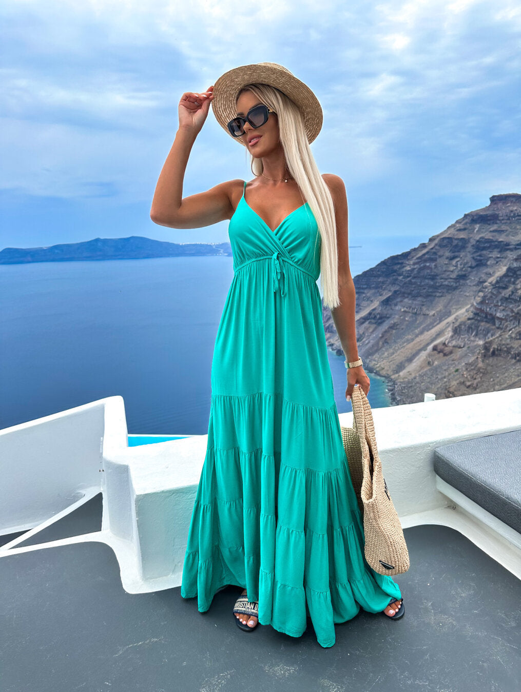Emerald green strappy summer dress with layered hem, outdoor coastal view